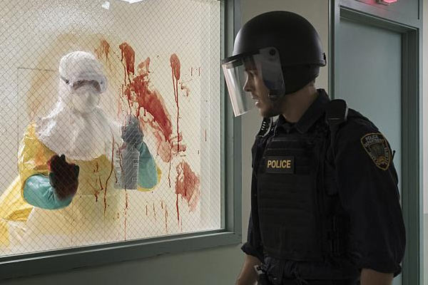 Containment, le flic regarde un médecin nettoyer du sang sur la vitre