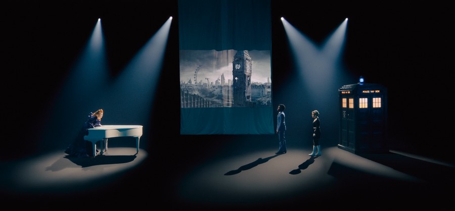 Scène théâtrale où Maestro, le Doc/Ruby et le TARDIS sont sous les projecteurs